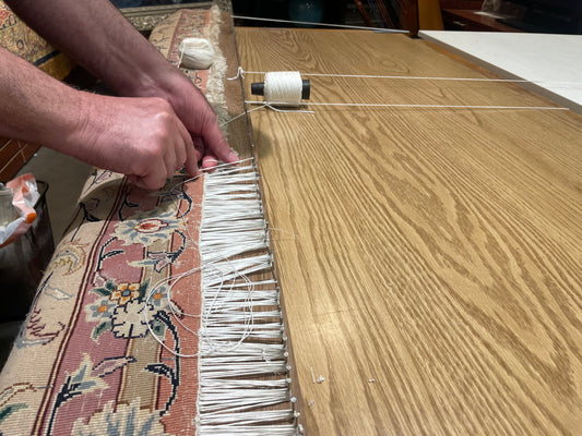 guy repairing handmade rug fringes